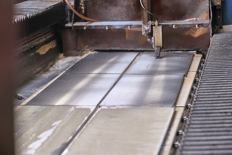 Industrieller Schleifprozess an einer großformatigen Metallplatte in einer Präzisionsschleifmaschine während der Oberflächenbearbeitung